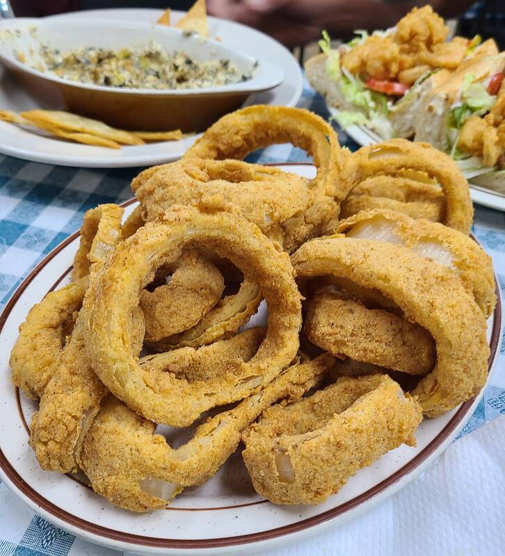 Onion rings and oyster Rockefeller dip with chips, a po-boy behind them.