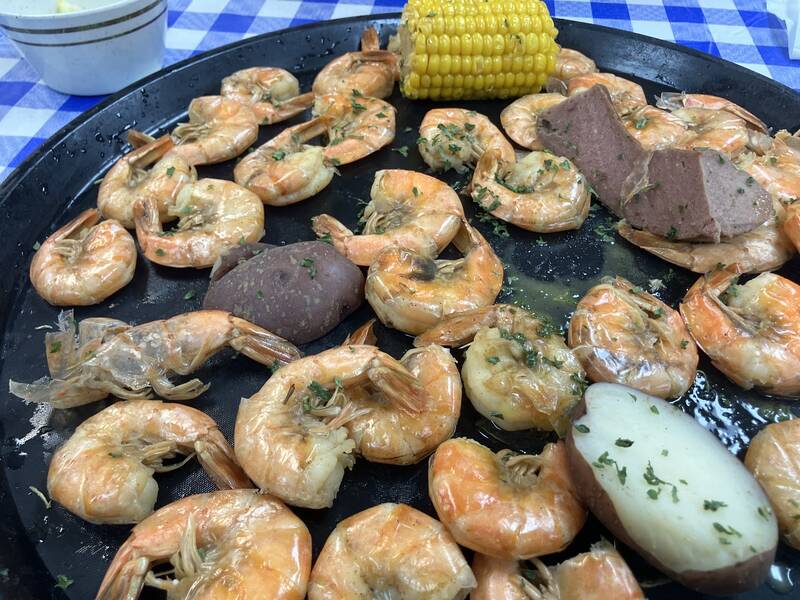 Boiled shrimp, corn, potatoes and sausage on a blue gingham tablecloth.
