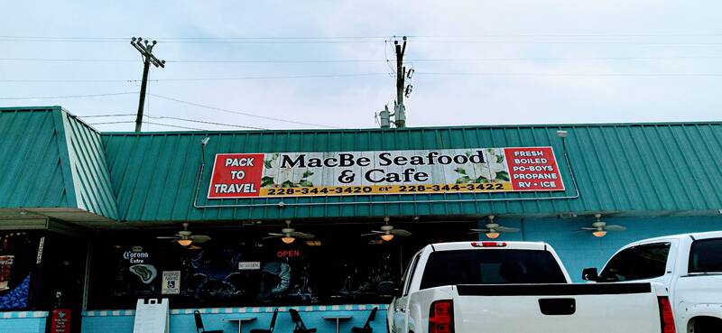 The MacBe Seafood & Cafe storefront with its teal roof and sign, trucks parked out front.